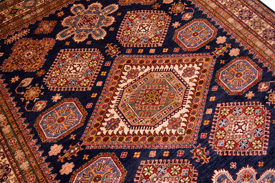 Close-up of navy kazak rug shows red, orange, and cream geometric motifs