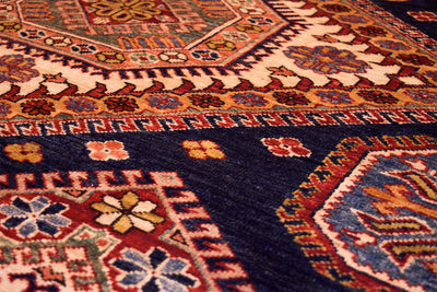 Corner close-up of navy kazak rug with repeating floral and lattice motifs