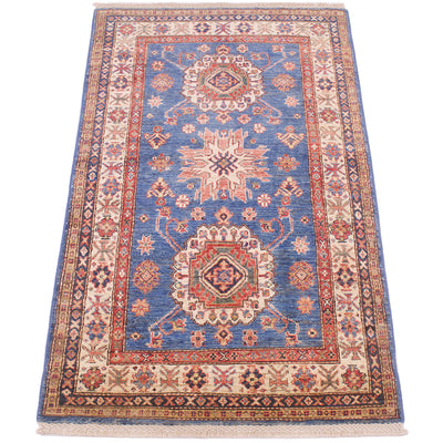 A traditional rectangular blue fine Kazak rug with a blue field, beige borders, and red and cream medallions, shown flat against a white background.