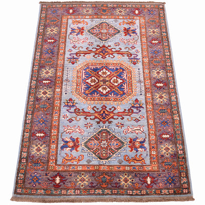 A traditional oriental fine Afghan Kazak rug with a light blue field, featuring a large central medallion and intricate geometric patterns in rust red, orange, brown, and navy blue. The rug is shown flat against a clean white background.
