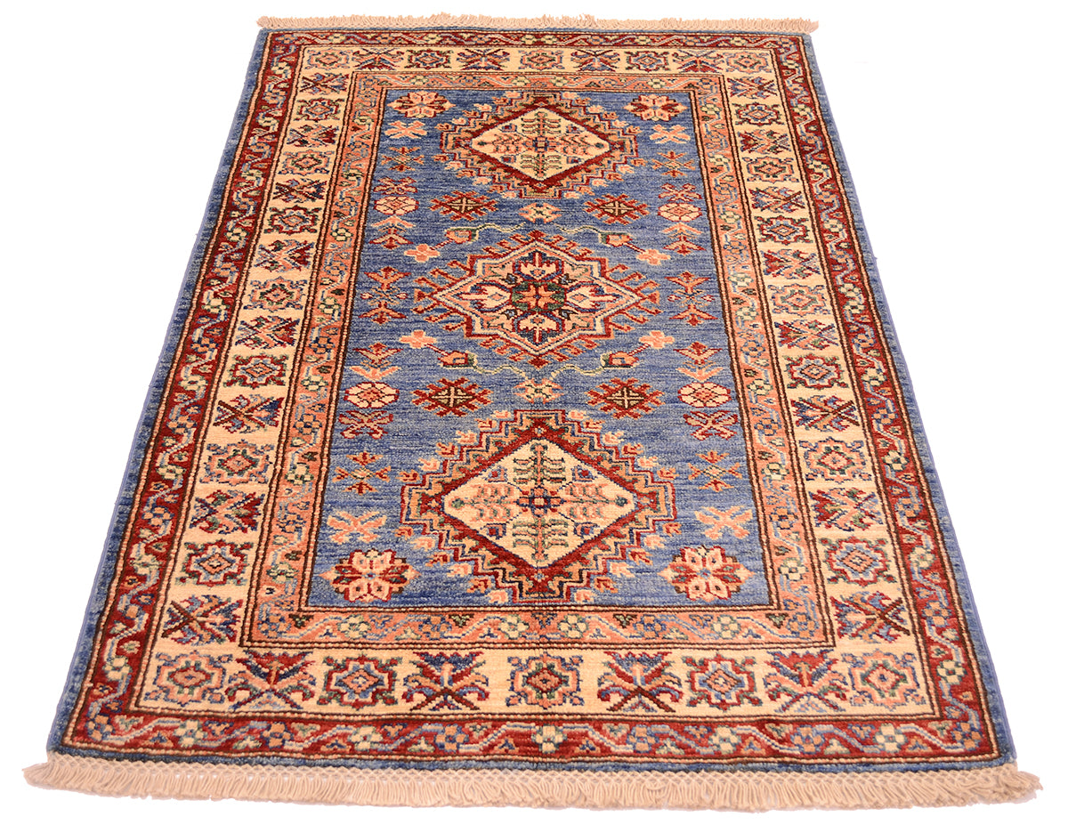 A traditional hand-knotted wool Afghan Fine Kazak Small rug with a geometric pattern, featuring a blue centre field, beige borders, and rust-red accents, shown flat against a white background.