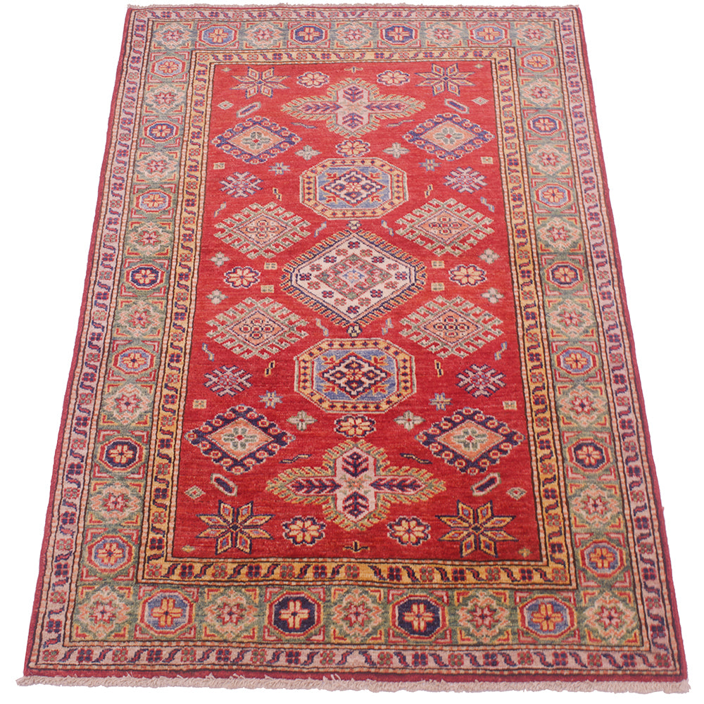 A traditional rectangular Afghan Kazak area rug with a vibrant red field, featuring a central medallion and geometric motifs in blue, beige, and green, surrounded by a patterned border.