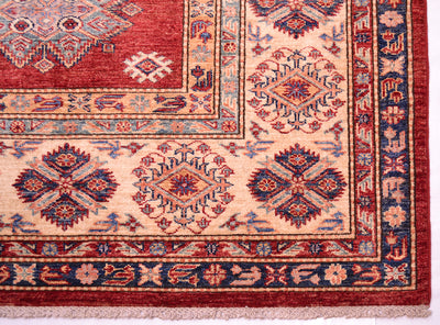 A close-up of a Large handmade red fine Kazak carpet showing a corner detail. The rug features a deep red field, a cream-colored inner border, and a dark navy blue outer border with intricate geometric and floral motifs in red, blue, and beige.