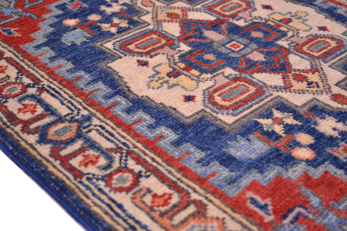 Close-up edge view of Kazak rug with blue, red, and cream geometric medallions.