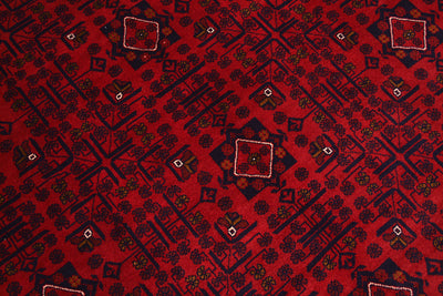 A close-up of a red afghan patterned rug featuring dark navy geometric and floral motifs with small white accents.