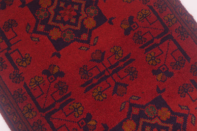A close-up of a red patterned afghan rug with dark navy geometric and floral motifs.