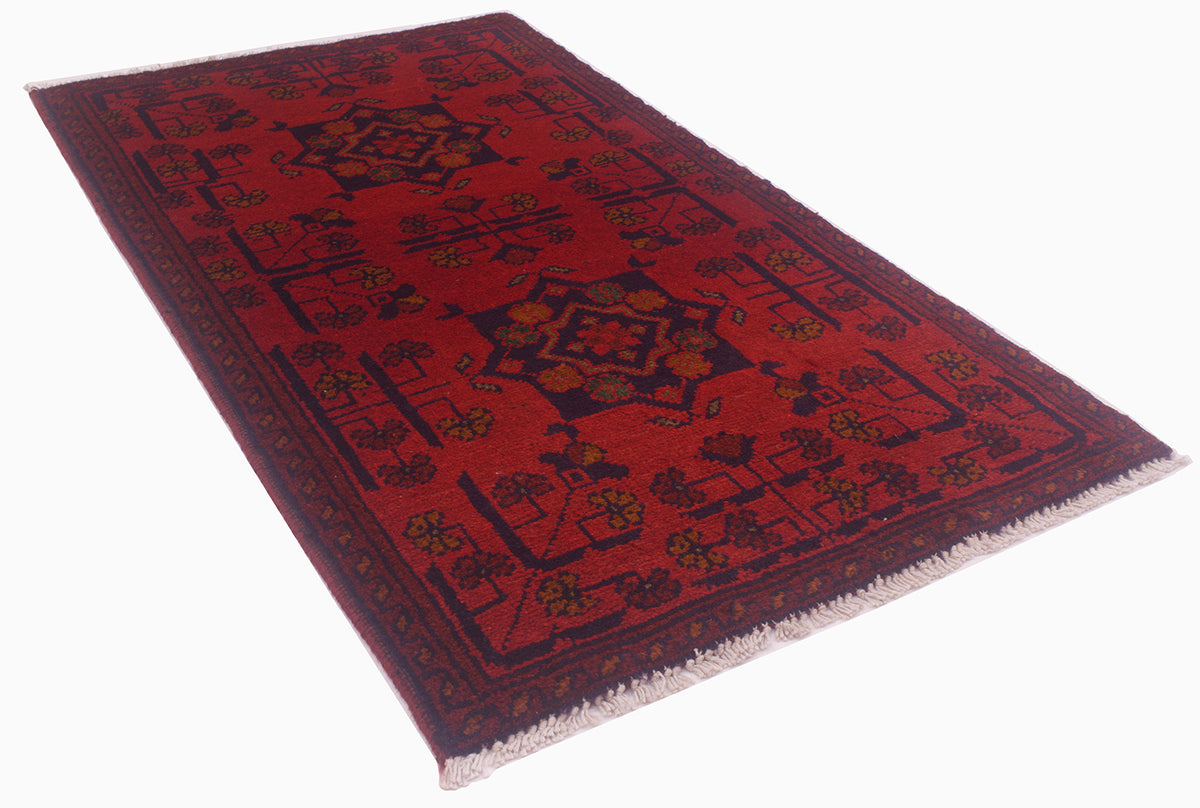 A traditional rectangular Afghan area rug with a deep red field, dark navy blue borders, and central medallions decorated with gold  floral motifs, finished with a white fringed edge.
