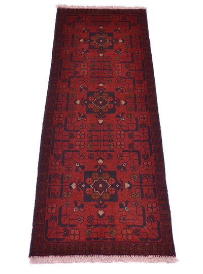 A traditional afghan runner rug with a deep red field, dark navy blue borders, and central medallions in beige, brown, and muted green, finished with light fringe on a white background.