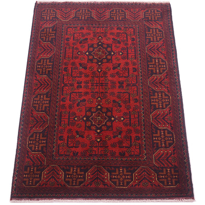 A traditional anfghan area rug with a deep red field, dark navy blue borders, and intricate geometric and floral motifs in gold and beige.