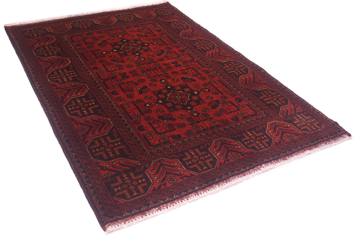 A traditional afghan-style wool area rug with a deep red field, dark navy borders, and intricate geometric patterns, shown from an elevated angle on a white background.