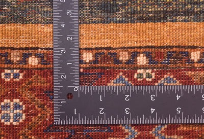 Close-up of the hand-knotted back of a patterned Khurjeen design rug with a dark L-shaped ruler placed over it to show scale of the knot density, showing detailed knotted texture and multicolour geometric motifs.