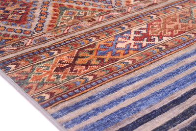 A close-up of a patterned Afghan Khorjin Runner rug with geometric and striped motifs in blue, beige, rust, brown, and cream.