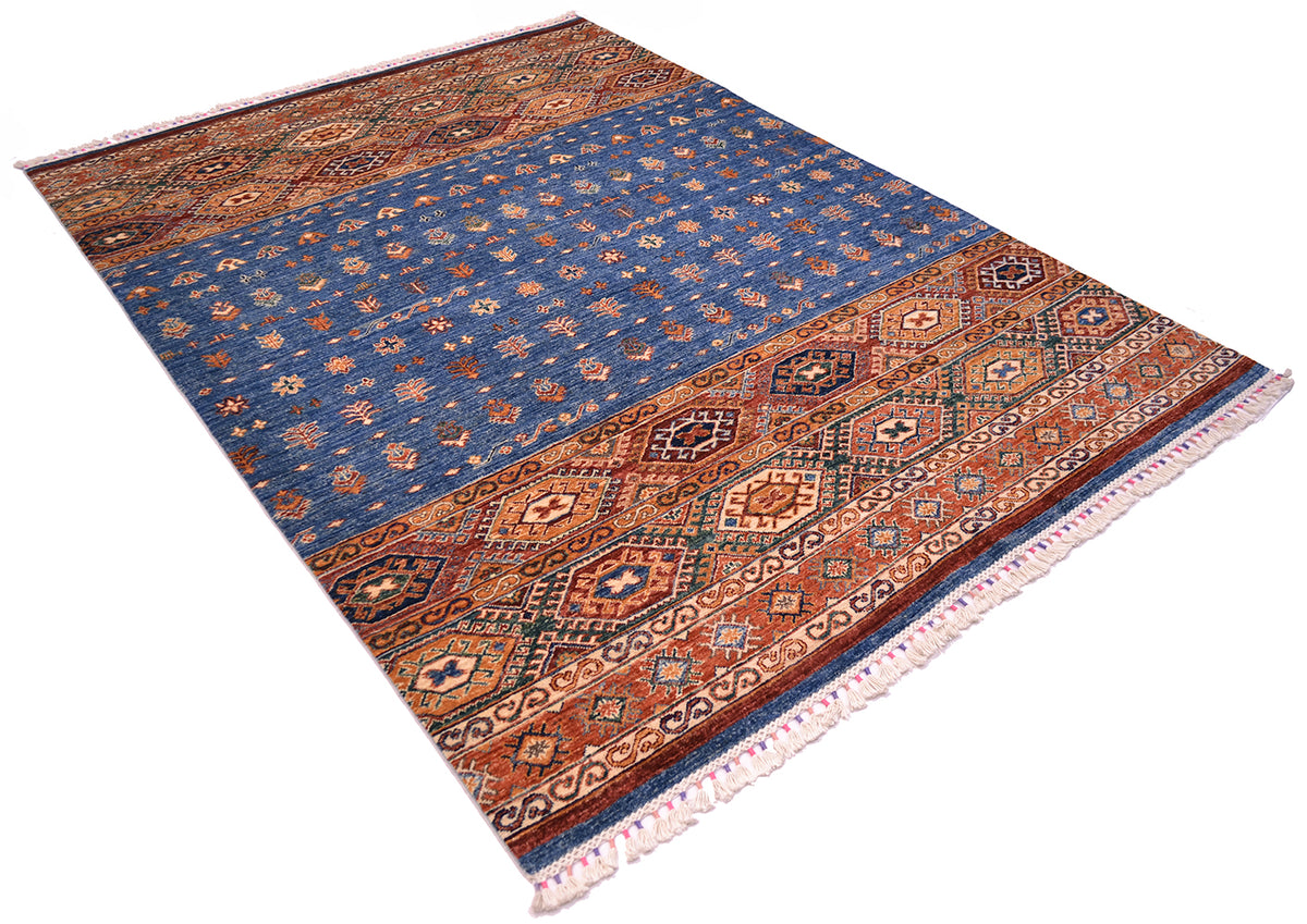 A rectangular Khorjin design carpet with a traditional geometric pattern, featuring a dominant blue field, rust and orange borders, and white fringe on the ends, shown on a plain white background.