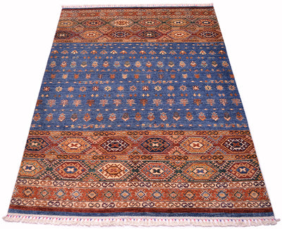 A rectangular Afghan Khorjin area rug with a traditional geometric pattern, featuring a dominant blue field with orange, red, and beige borders and motifs, finished with white fringe on the top and bottom.