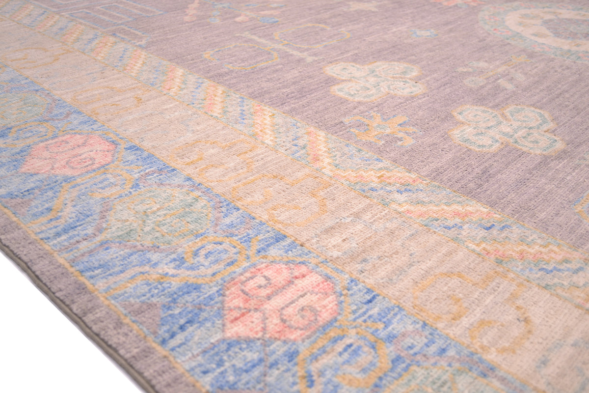 Close up detail of main border of Khotan design Carpet with blue, gold and coral pinks and soft grey field colour. Handknotted carpet with natural vegetable dyes.