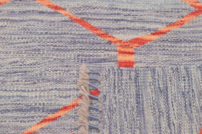 Close-up of a handwoven modern design Kilim runner with a heathered blue-grey base, bright orange geometric lines, and a fringed edge.