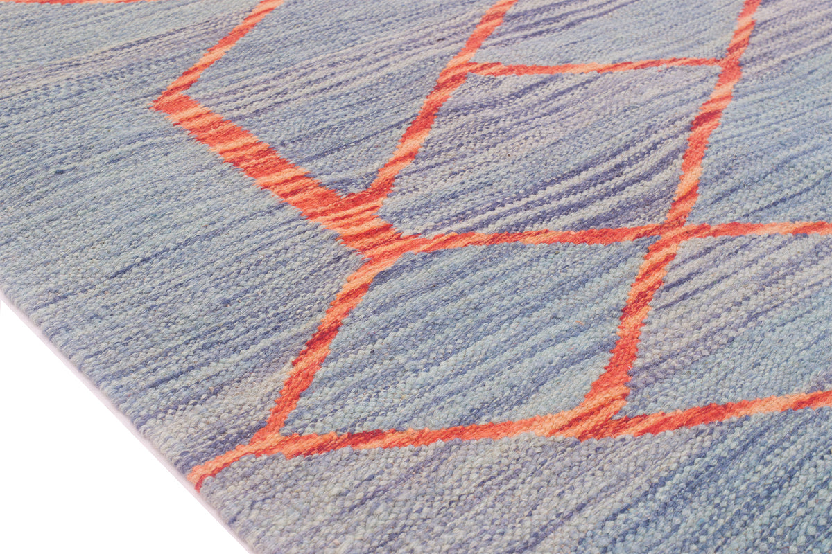 Close-up of a modern Kilim runner rug with a blue-grey woven background and a geometric pattern outlined in bright coral orange.