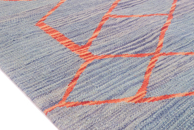 Close-up of a modern Kilim runner rug with a blue-grey woven background and a geometric pattern outlined in bright coral orange.