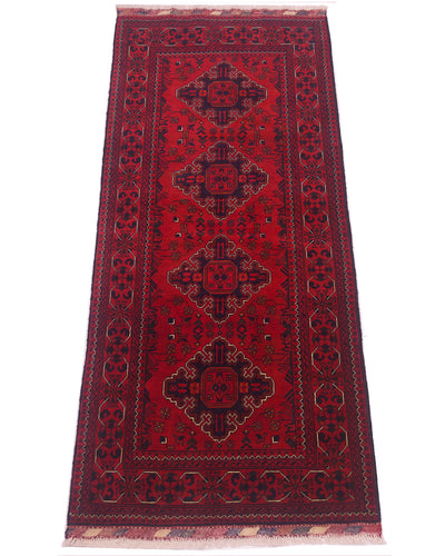 A traditional afghan runner rug with a deep red field, featuring four central medallions in dark navy and black, surrounded by a patterned border and fringed ends.