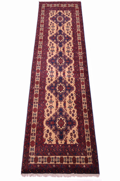 A long rectangular area runner with an intricate geometric and floral pattern in deep red, navy blue, beige, and cream, shown flat against a white background.