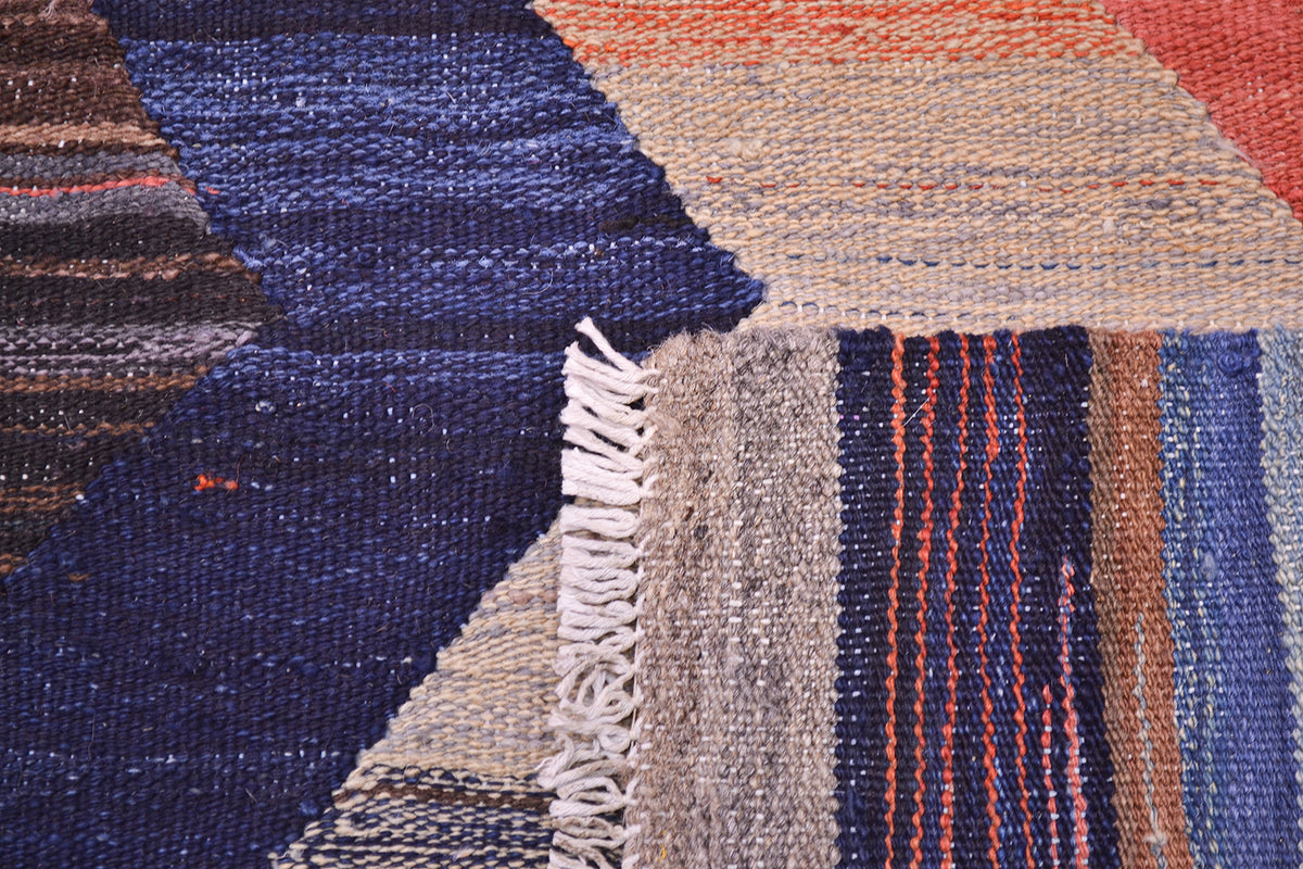 Kilim rug fringe and woven texture detail in cream, navy, red, and orange