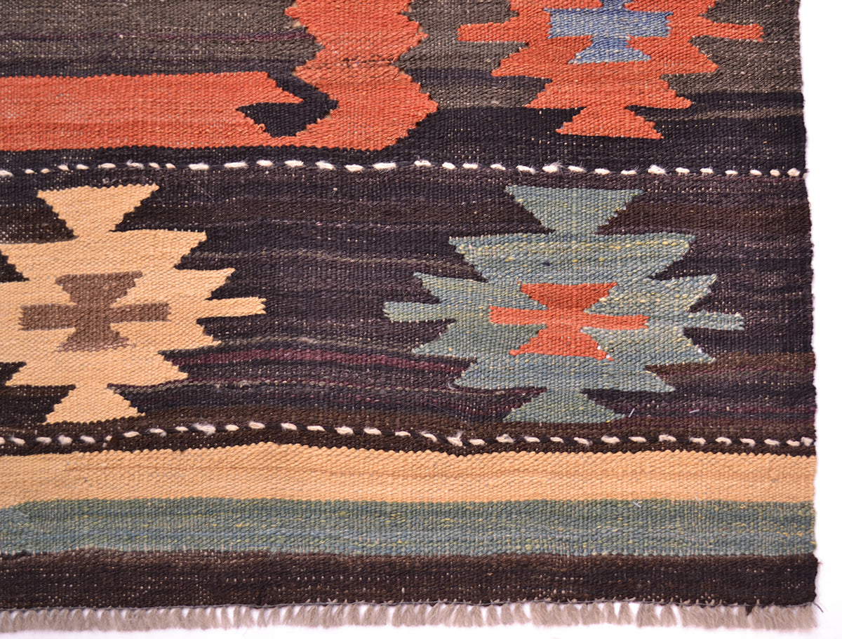 Close-up of a handwoven Afghan Labijar kilim rug showing geometric patterns in dark brown, terracotta orange, beige, and muted blue-green.