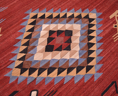 A close-up of a woven Afghan Kilim 3x2m rug featuring a geometric diamond pattern with concentric squares of beige, brown, black, and red, bordered by blue-grey triangles on a red background.