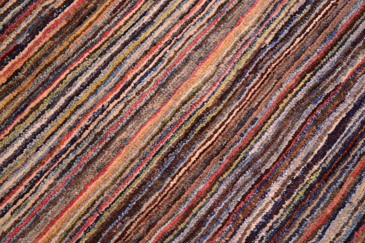 A close-up of a textured Afghan Gabbeh area rug featuring diagonal stripes in a multicolour pattern of brown, beige, red, blue, and yellow.