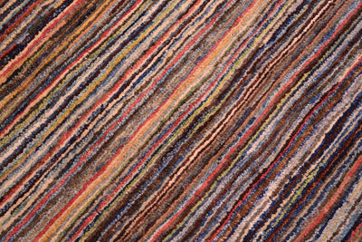 A close-up of a textured Afghan Gabbeh area rug featuring diagonal stripes in a multicolour pattern of brown, beige, red, blue, and yellow.