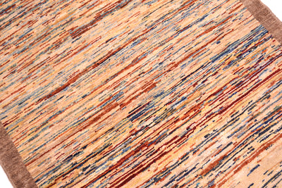 A close-up of a textured Afghan stripy Gabbeh rug with a warm beige base, featuring diagonal streaks of rust red, blue, and brown, finished with a solid brown border.
