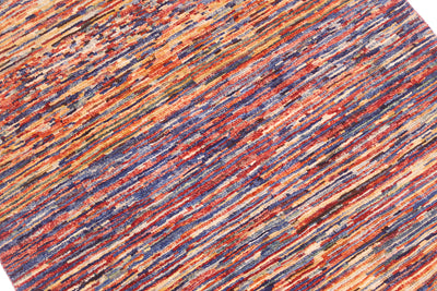 A close-up of a textured hand-knotted Afghan Gabbeh rug with a multicolour abstract pattern of diagonal stripes in rust red, orange, blue, and cream.