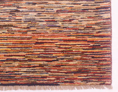A close-up of a 3x2m handmade modern Afghan Gabbeh carpet showing its detailed woven pattern with horizontal stripes in rust orange, beige, brown, and dark navy, finished with a fringed edge.