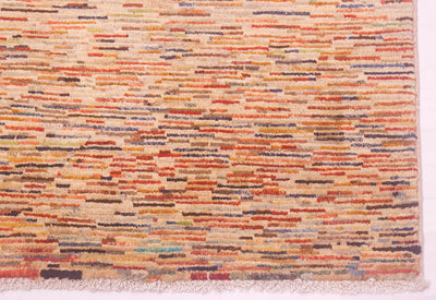 A close-up of a handmade Afghan Gabbeh carpet with horizontal multicolour stripes in orange, red, blue, and brown on a cream base, finished with a fringed edge.
