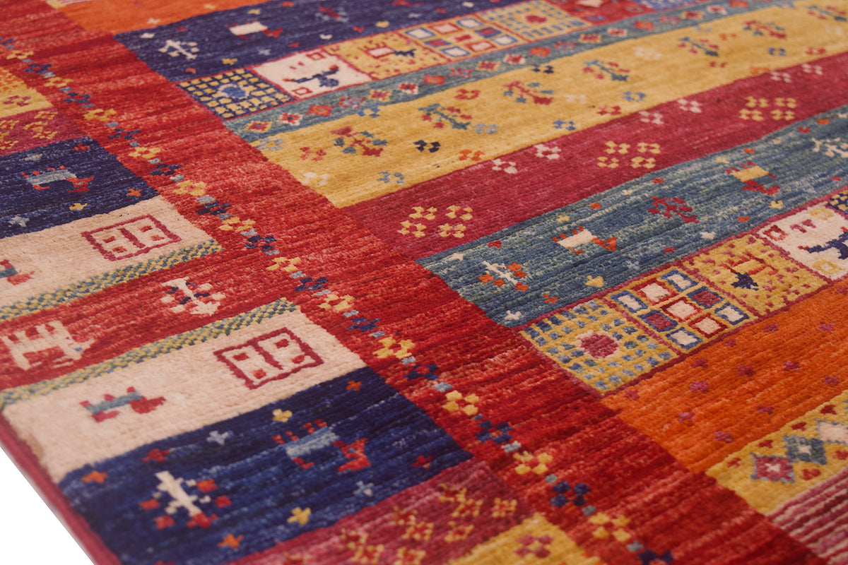 A close-up of a colourful patterned Afghan Loribaft-Gabbeh rug with geometric and tribal-inspired motifs in red, blue, yellow, orange, and cream.