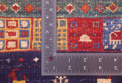 A close-up of a hand-knotted back of a Afghan colourful Loribaft rug with a dark metal ruler placed vertically and horizontally to show the scale of the fineness of the knotting.