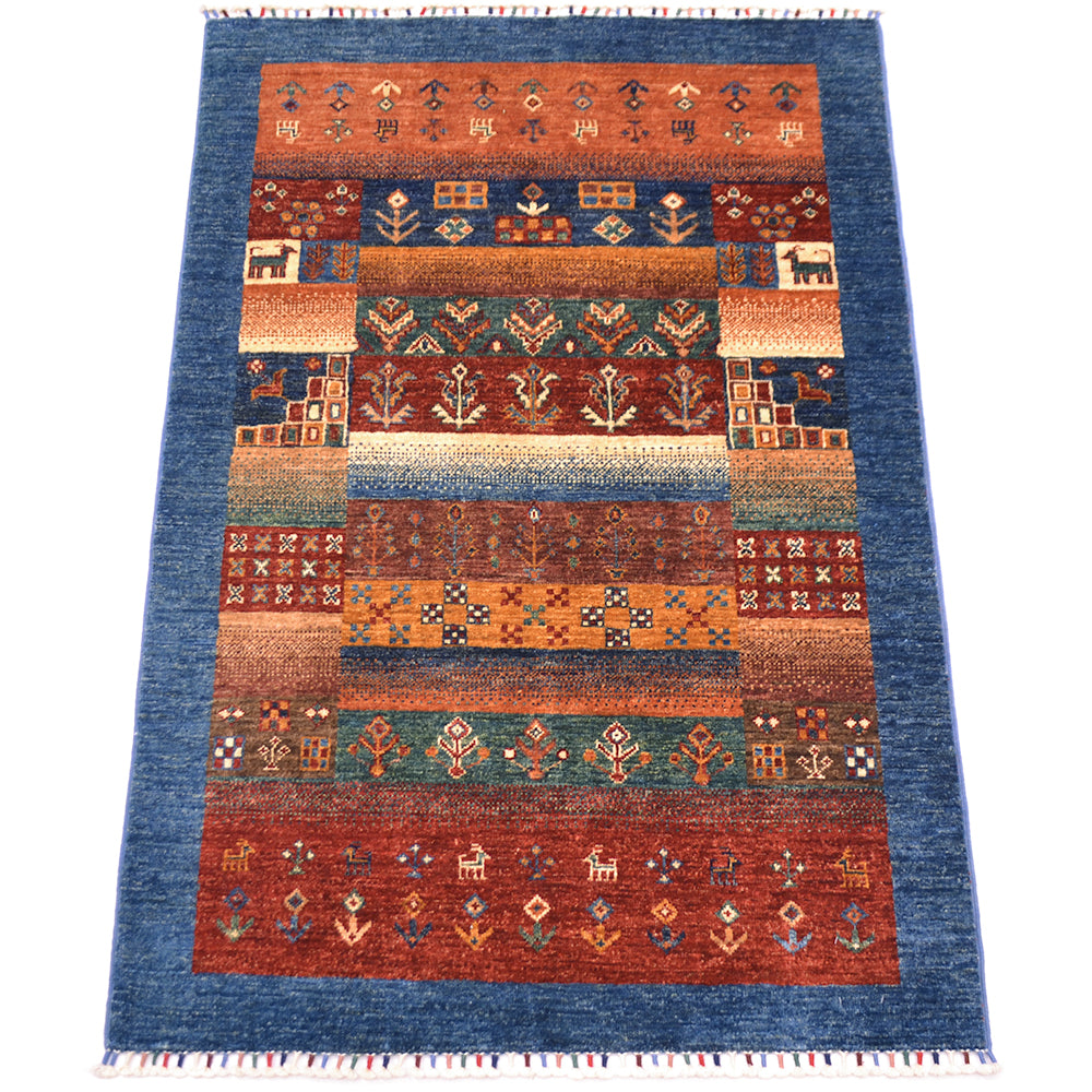 A 5x3 rectangular handwoven Loribaft rug with blue border and intricate geometric and animal motifs in rust red, orange, brown, and teal, shown flat against a white background.