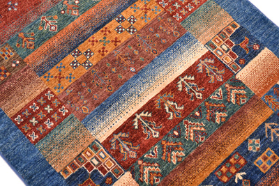 A close-up of a patterned Afghan Loribaft rug with plain blue border, rust red, orange, teal, and beige, featuring geometric and tribal-inspired motifs.