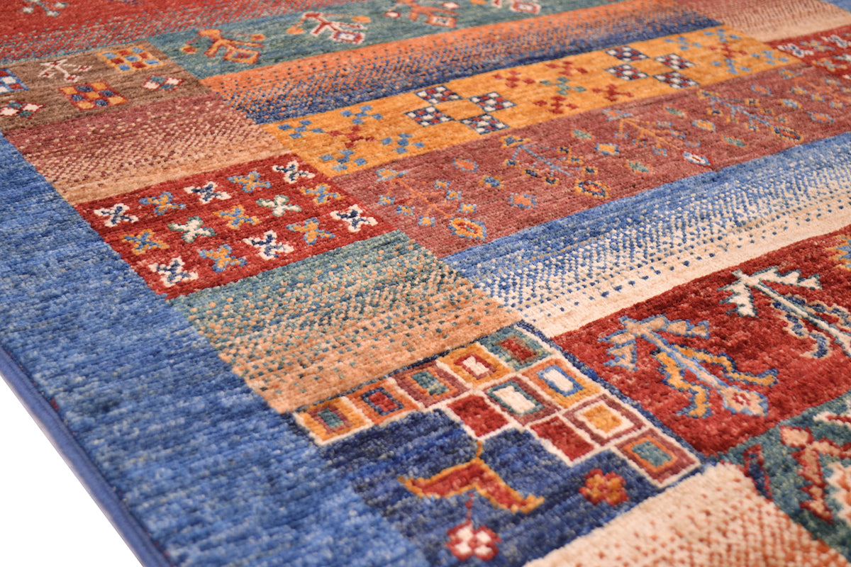 A close-up of a multicolour tribal themed Afghan Loribaft area rug with geometric and floral motifs in blue, rust red, orange, beige, and teal tones.