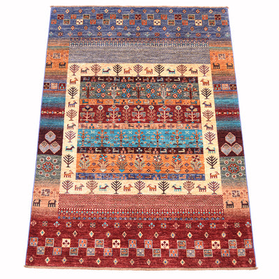 A 7x5 rectangular hand-woven multicolour  Loribaft area rug with a complex geometric and animal motif, featuring a central cream panel surrounded by bands of blue, orange, red, and brown patterns with stylised deer /goats and trees.