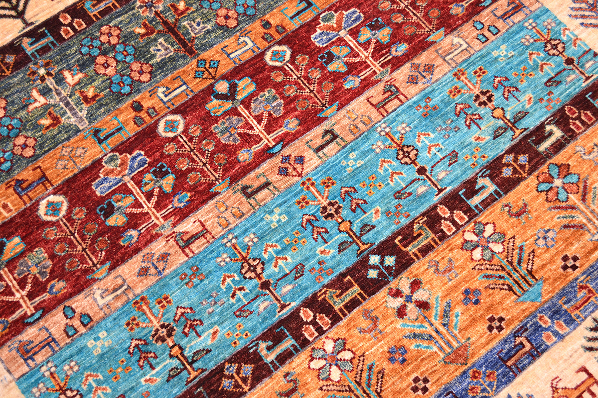 A close-up of a handmade patterned Afghan Loribaft area rug with multiple horizontal bands of geometric and floral motifs in rust red, turquoise blue, peach, navy, and cream.