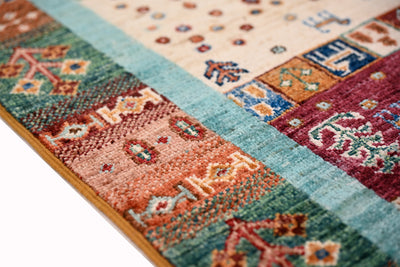 Afghan Loribaft Gabbeh handmade rug side detail, multicolour motifs on textured field with mustard selvedge edging.