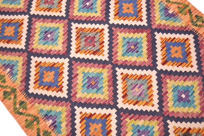 A close-up of a multicolour Afghan Kilim Short Runner a repeating geometric stepped diamond pattern in multiple colours including orange, blue, yellow, pink, purple, and cream, with a decorative border.