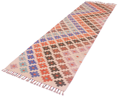 A 10ft long handwoven Kilim Hallway Runner rug with a geometric diamond pattern in pink, orange, blue, brown, and beige, finished with fringed ends, shown on a plain white background.