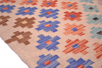 Close-up of a woven Kilim long runner rug with a geometric pattern in blue, coral orange, brown, and light blue on a beige background.