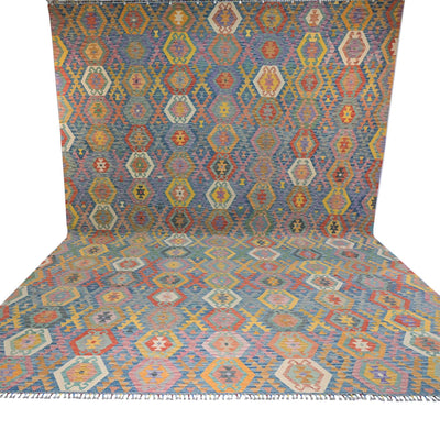 A Giant Handwoven Afghan Kilim rug with a colourful geometric diamond pattern, shown draped to display both its flat surface and its fringed edge against a white background.