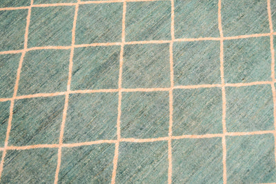 Close up detail of main field and lattice geometric pattern of handmade afghan carpet  in light topaz turquoise and cream tonalities. Pure wool pile. 