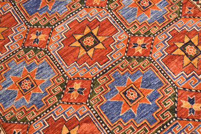 Close up detail of Memling geometric gul  in main field of handmade afghan carpet with blues,  forest green, rust reds and golden ochres.