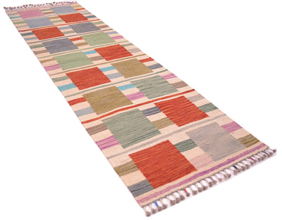A 6'6 long handwoven Modern Kilim short runner rug with a geometric design in muted tones of red, sage green, pink, beige, and grey, finished with tasseled ends on a white background.