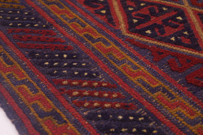 Close-up of a woven Afghan Mushwani square rug with geometric patterns in dark navy blue, red, ochre yellow, and cream.