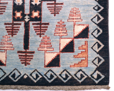 Close-up of a corner of an Afghan Blue Aryana long runner showing a geometric pattern with stylised tree-like shapes in terracotta, cream, and black on a light blue field, with a dark border and fringe.